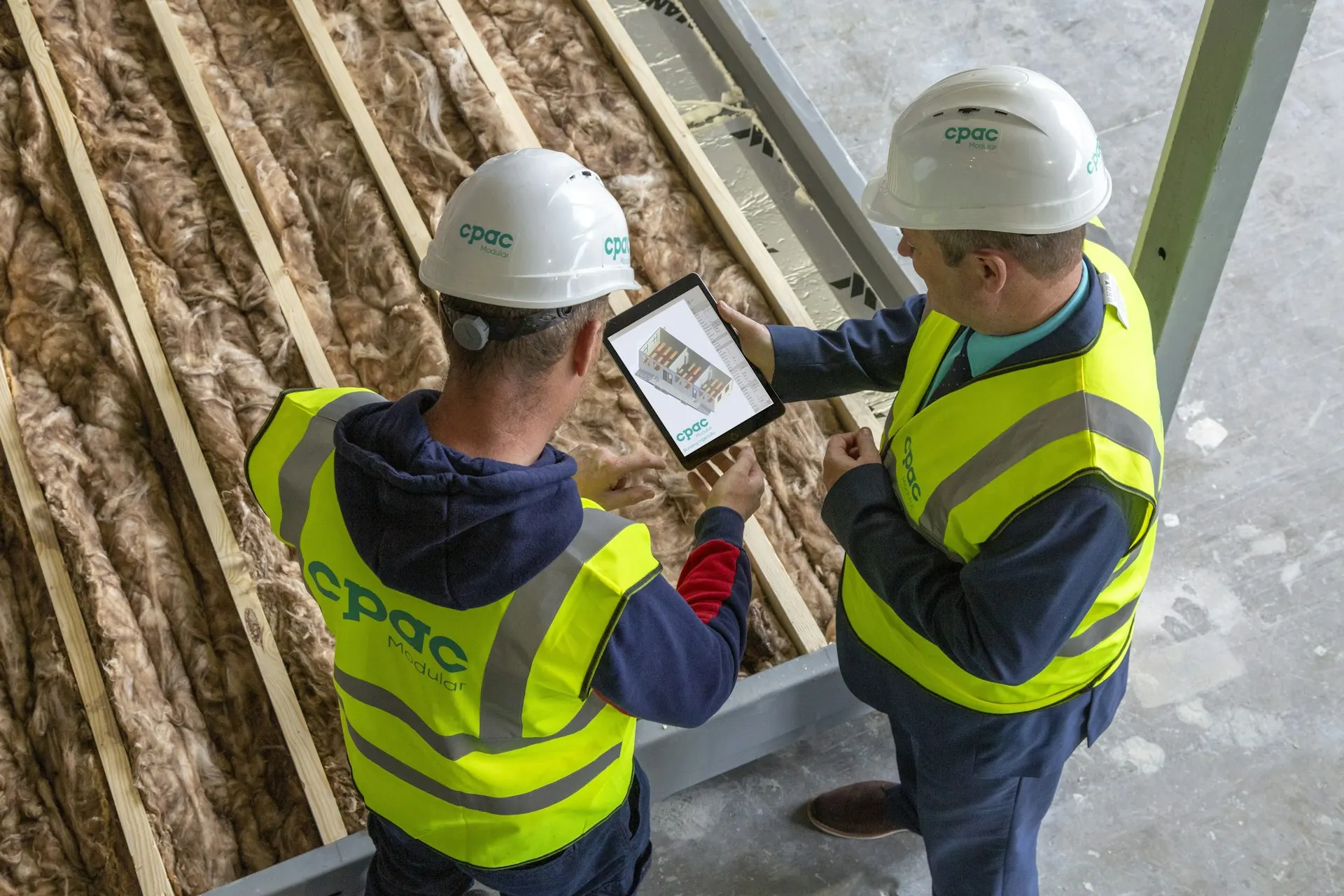 Two people in hard hats checking plans on site